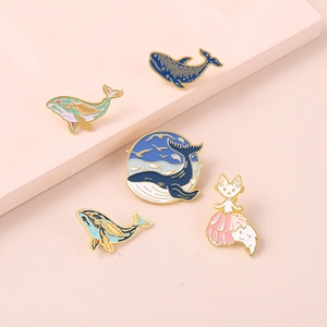 Detailed set of five ocean-themed enamel pins featuring blue whales and a pink cat