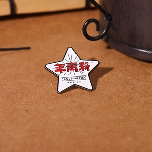 La Jeunesse star-shaped enamel brooch with red Chinese characters on a brown surface
