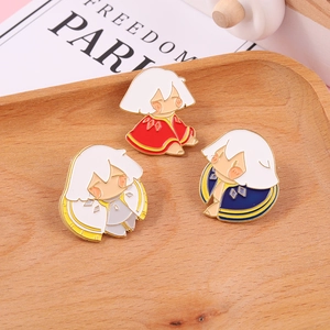 Detailed close-up of three Sky Children of the Light enamel pins on a wooden tray