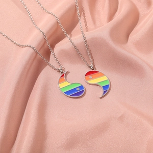 Dettaglio di due ciondoli Yin Yang arcobaleno su catene d'argento su seta rosa