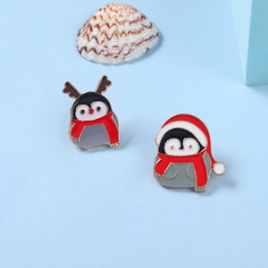 Detail of Christmas penguin enamel pins with festive hats and scarves on light blue base
