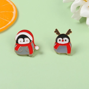 Close-up of two enamel penguin brooches with festive Christmas hats and red scarves