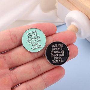 Set of two round enamel inspirational quote brooches in mint green and black finish