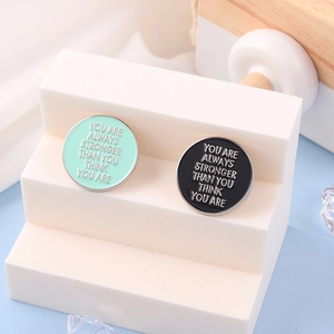 Detail of round enamel badges in mint green and black with motivational quotes