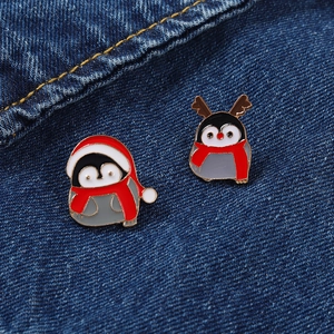Makroaufnahme süßer Weihnachts-Pinguin-Emaille-Pins auf blauem Denim-Hintergrund