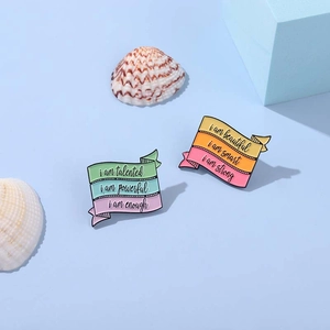 Close-up of pastel enamel ribbon pins with motivational quotes on blue background