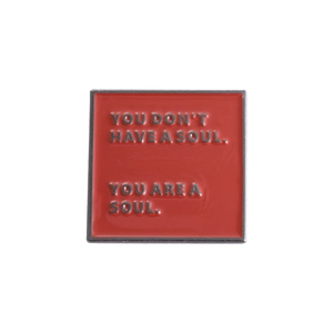 Detailed close-up of square red enamel brooch with embossed soul quote lettering