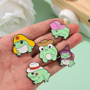 Lot de cinq broches grenouilles en émail avec chapeaux variés tenues à la main sur fleurs