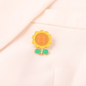 Cute sunflower enamel pin badge with vibrant yellow petals on pink fabric background