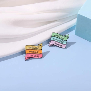 Macro shot of two enamel pins with rainbow gradients and inspirational English mottos