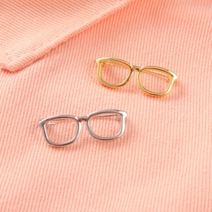 Minimalist gold and silver metal eye pins on pink striped fabric for clothing decor