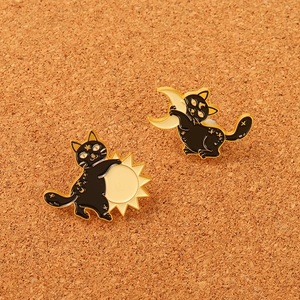 Détail de broches chat noir avec motifs soleil et lune sur support en liège
