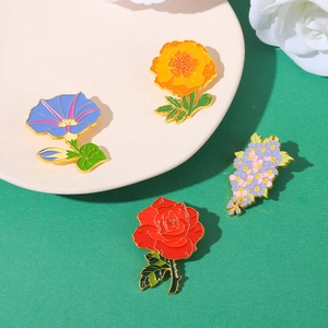 Detail of floral enamel pins featuring poppy and morning glory with gold-plated edges