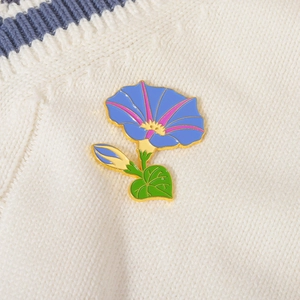 Elegante spilla smaltata con fiore di convolvolo blu su maglione bianco a trecce