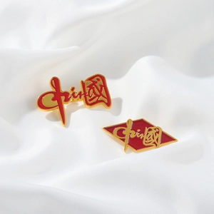 Close-up of red and gold enamel Chinese badges on white silk fabric background