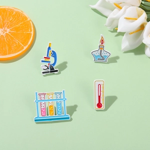 Science enamel pins set featuring microscope, test tubes, and lab lamp on green background