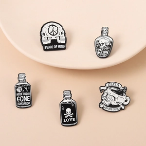 Detail of five black and white enamel pins featuring skull and death potion motifs