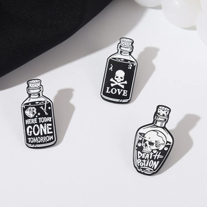 Close-up of gothic skull enamel pins with Love and Death Potion designs on white background