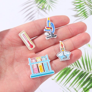 Laboratory science pin set with microscope and thermometer pins shown on a hand