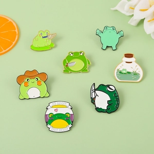 Detailed close-up of colorful cartoon frog enamel pins set on a fresh green background