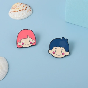 Ensemble de pin's émaillés garçon et fille sur fond bleu avec coquillages