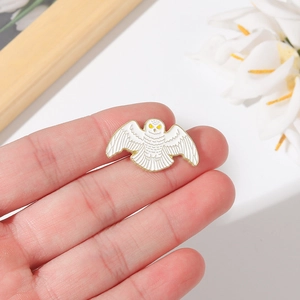 Cute white owl enamel pin with gold detailing and wings spread in a flying pose