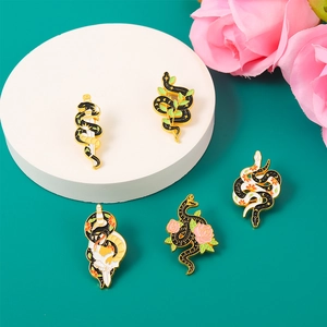 Detailed close-up of snake enamel pins featuring swords, leaves and floral accents