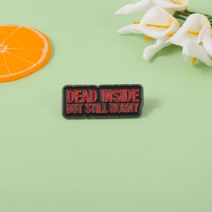 Rectangular enamel pin with Dead Inside But Still Horny text on green background