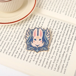 Detail of an enamel bunny crest brooch on an open book showing golden metal edges