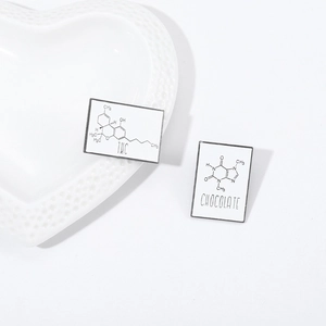 Detail of square enamel pins featuring THC and Chocolate caffeine chemical formulas