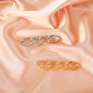 Minimalist metal safety pin brooch accessory in gold and silver on pink silk fabric
