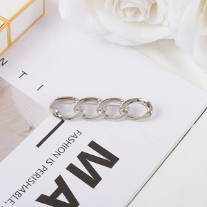 Close-up of polished silver Cuban chain link brooch on a stylish fashion magazine background
