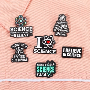 Detailed set of 6 science enamel pins with atoms and flasks on pink denim background