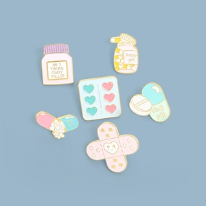Detailed view of six medical themed enamel pins including pills and band-aid designs