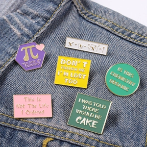Set of 6 colorful enamel math and formula pins displayed on casual denim fabric