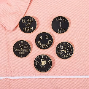Set of six black and gold enamel pins with creative slogans on pink denim background