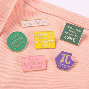 Set of six colorful enamel pins with mathematical formulas and witty quotes on denim jacket