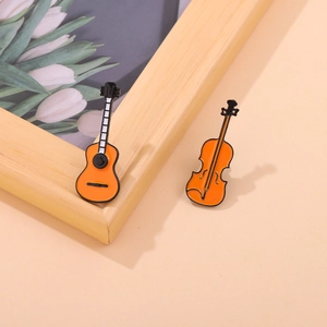 Detail view of orange enamel musical instrument pins featuring guitar and violin shapes