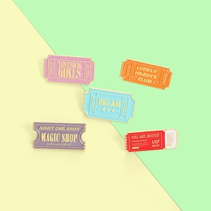 Set of five retro stamp-shaped enamel pins in purple, orange, and blue with gold edges