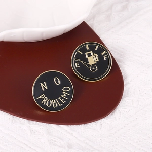 Macro view of enamel pins featuring a car fuel gauge and No Problemo text design