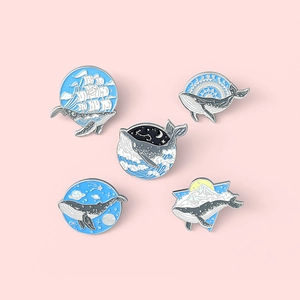 Creative enamel whale brooches set featuring ocean and starry sky designs on pink background