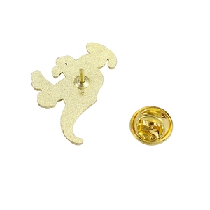 Détail macro du dos du badge en métal doré montrant le fermoir papillon et l'attache