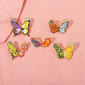 Broches papillon en émail coloré avec pronoms sur fond en denim rose vif