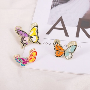 Trois broches papillons en émail coloré avec motifs de pronoms d'identité divers