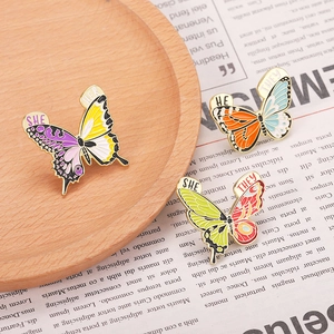 Détail de pins papillon émaillés colorés avec pronoms sur un plateau en bois rustique