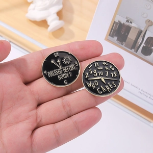 Black enamel clock brooches with 'Who Cares' and 'Dressed Before Noon' slogans in gold finish