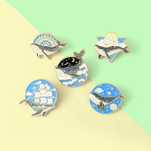 Set of 5 creative whale enamel pins featuring ocean waves, starry skies, and sailboats