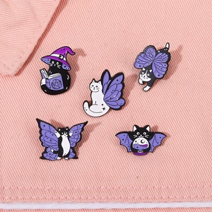 Detailed view of five cute purple wizard and bat cat enamel pins on pink denim fabric