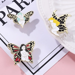 Detail shot of three artistic butterfly fairy enamel pins on a white ceramic plate
