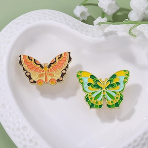 Gros plan de deux broches papillons colorées en émail sur une assiette décorative